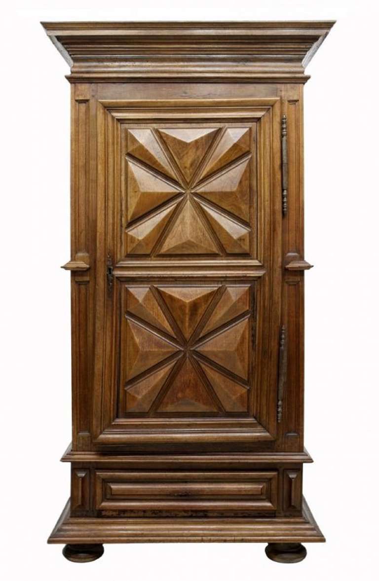 18th Century French Provincial Bonnetiere, likely Brittany, a stepped crown over a single door with large exposed hinges, a lower drawer, raised on with a wide stepped base, the front and side with raised geometric panels