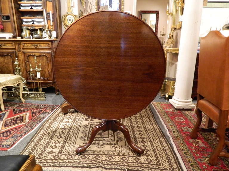Circa 1800 George II mahogany breakfast, center, or dining table, the dished circular top supported by tapered ring and urn standard rising on snake legs ending in pad feet on casters
