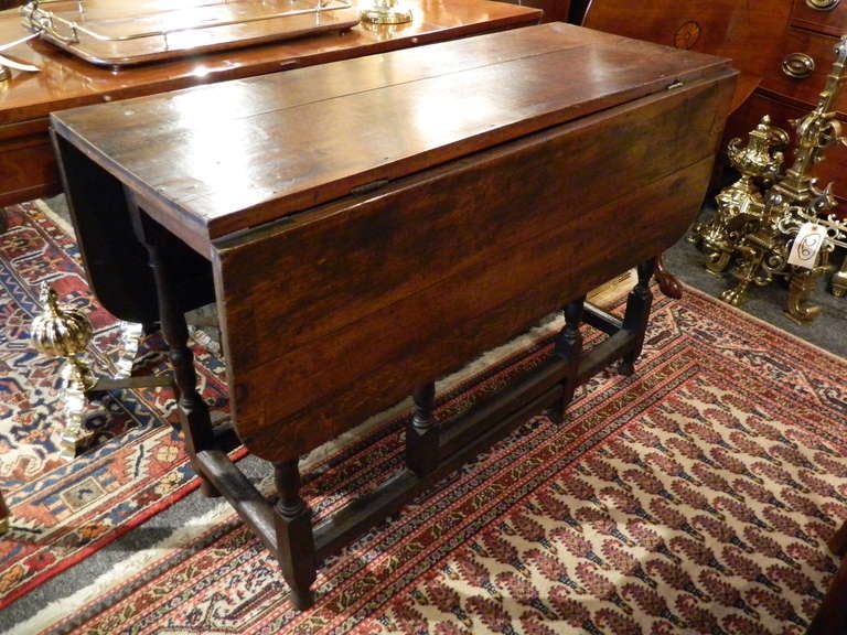 18th Century George I Oak Gate Leg Table, having a rectangular top over two leaves with rounded corners, the frieze set with a single drawer, raised on block and turned gate-legs joined by stretchers 