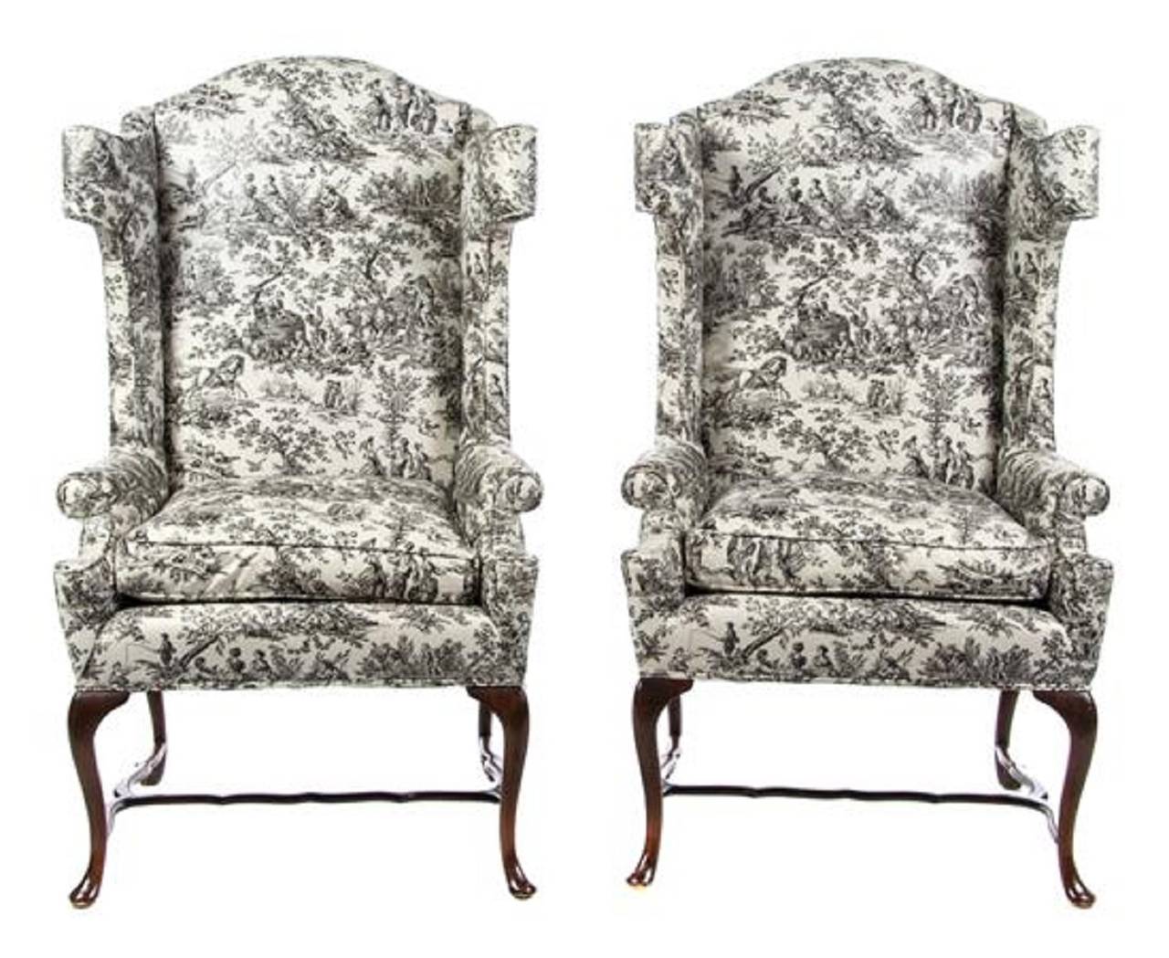 A pair of George III style wingback armchairs, Early 20th century. Each with glazed chintz toile upholstery, raised on cabriole legs joined by stretchers.