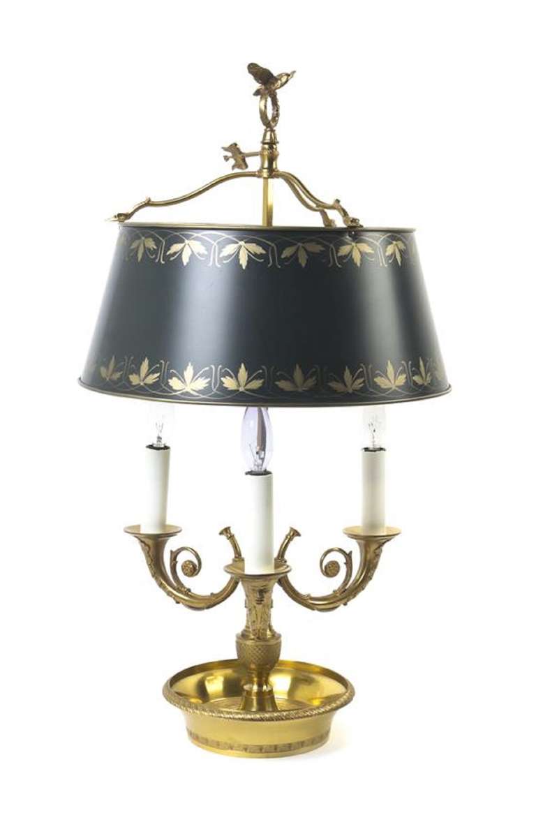 19th Century Empire Style Gilt Bronze Bouillotte Lamp, having three scrolled candle arms with mask decorated nozzles over the dished base, with a hand painted tole shade