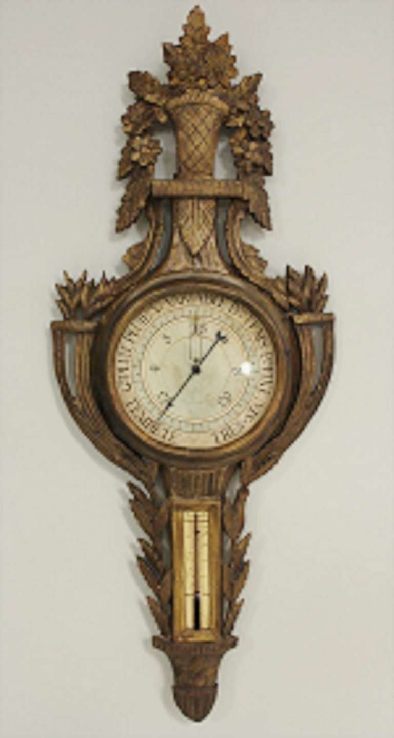 19th century Louis XVI style wall barometer with gilt finish, wooden, crowned with basket of flowers.