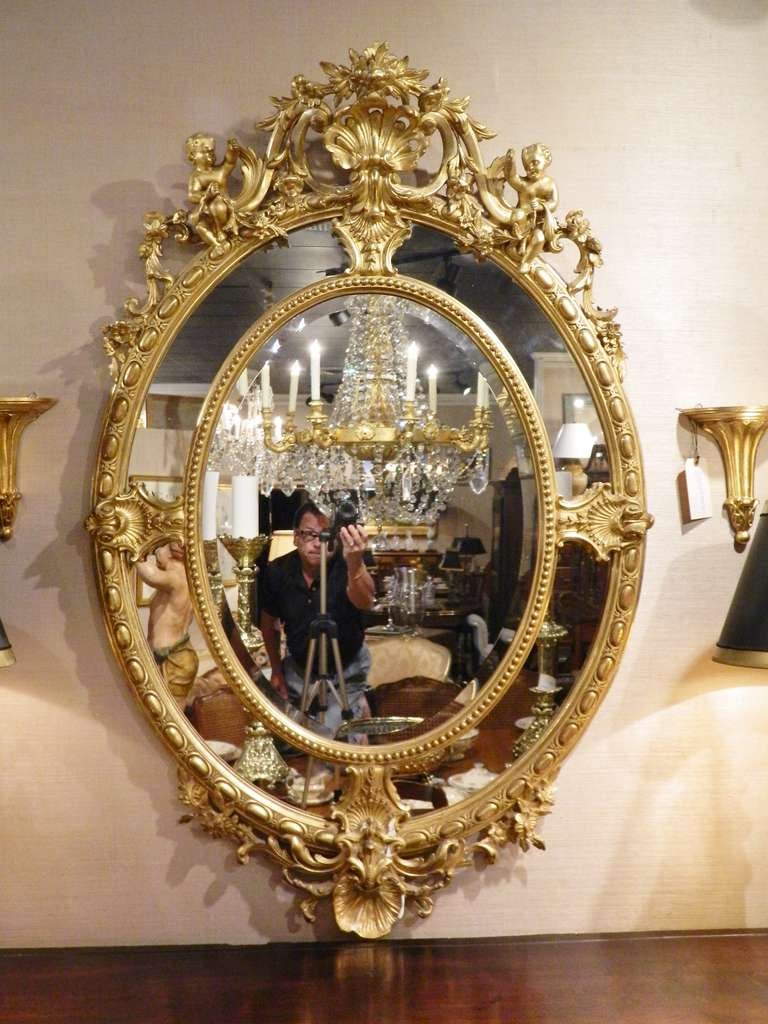 19th century wonderful English 24-karat water gilt Regency style oval mirror adorned with cherubs and shells.