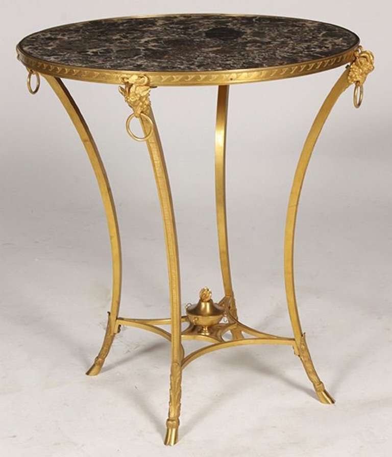 Late 19th/Early 20th Century Empire Style Bronze Gueridon Having Inset Marble Top framed by bronze trim supported on rams head decorated downswept legs. The legs having a central stretcher with finial and hoof feet