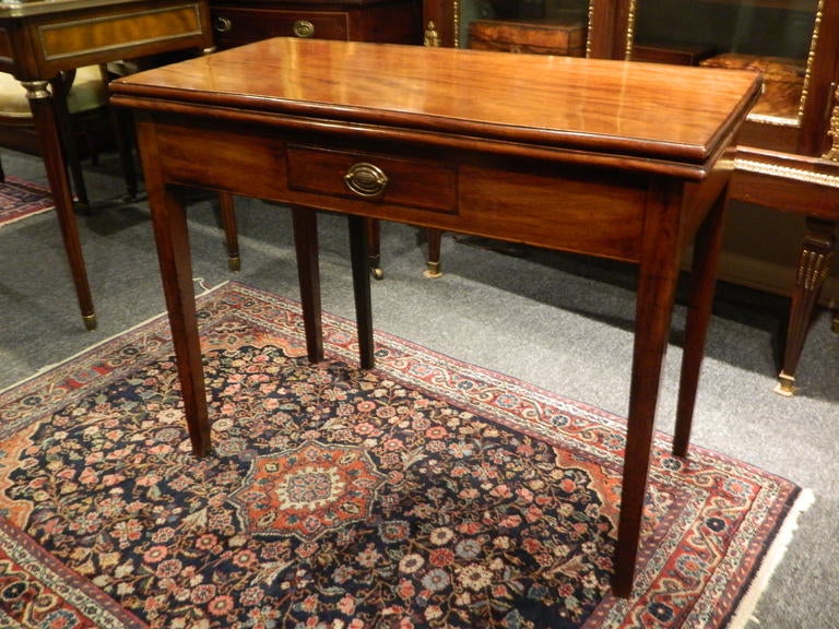 18th century English fold over mahogany games or tea table with original finish and a small drawer. The rectangular top raised on straight legs. There is one rear leg that swings out to support the top when opened. Dimensions when closed 36