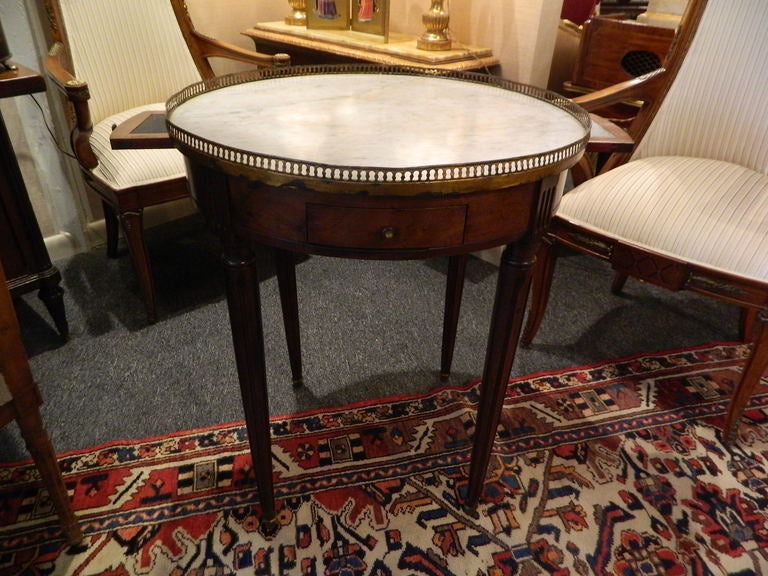 Louis XVI-Stil Mahagoni und Marmorplatte Bouillotte Tisch, 19. Jahrhundert.  Die kreisförmige Platte aus weißem, panaschiertem Marmor befindet sich in einer durchbrochenen Messinggalerie, über einem Fries mit zwei kleinen Schubladen und zwei