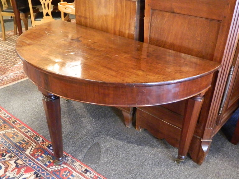 19th Century Louis Philippe Demi-Lune Table in Walnut. Legs are turned and rest on casters