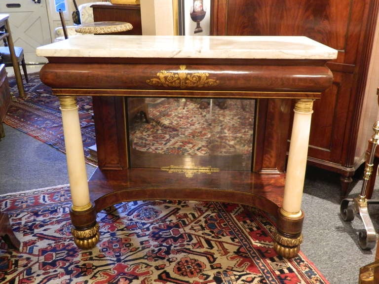 Pier table or console with a marble top and composed of vibrantly figured mahogany with marble columns; bronze doré decorations, and flanking a mirror, circa 1830.