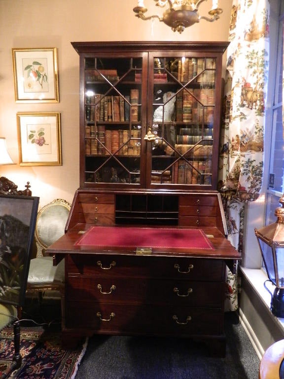 English Secretary Bookcase. Slant top desk with leather writing surface features a number of drawers and cubbyholes. Four(4)drawers below desk. Upper cabinet has three adjustable shelves.  Carved dental work on cornice molding.  Original Hardware