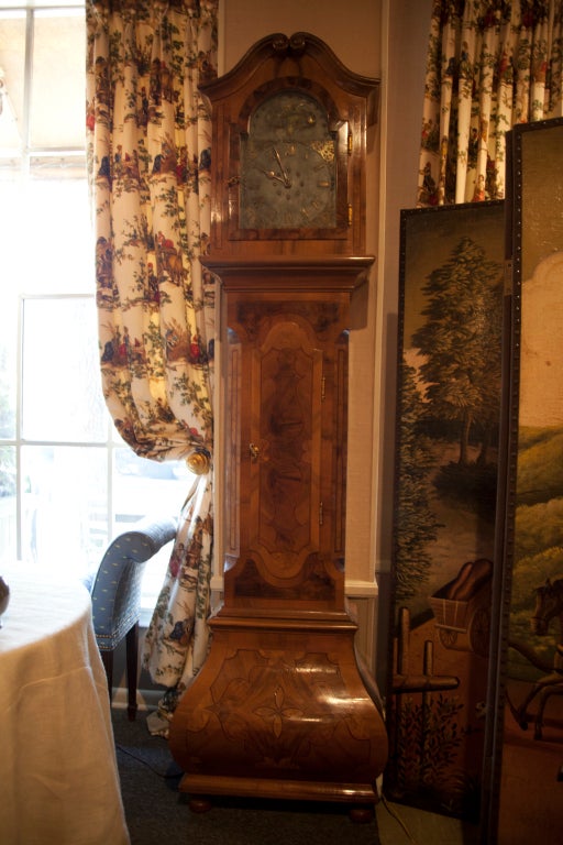 German Baroque style inlaid walnut tall case clock, 19th Century.  The bonnet with a scroll molded cornice above an arched glazed door opening to a pewter and brass dial with a Roman chapter ring, foliate spandrels and a maiden playing a horn in the