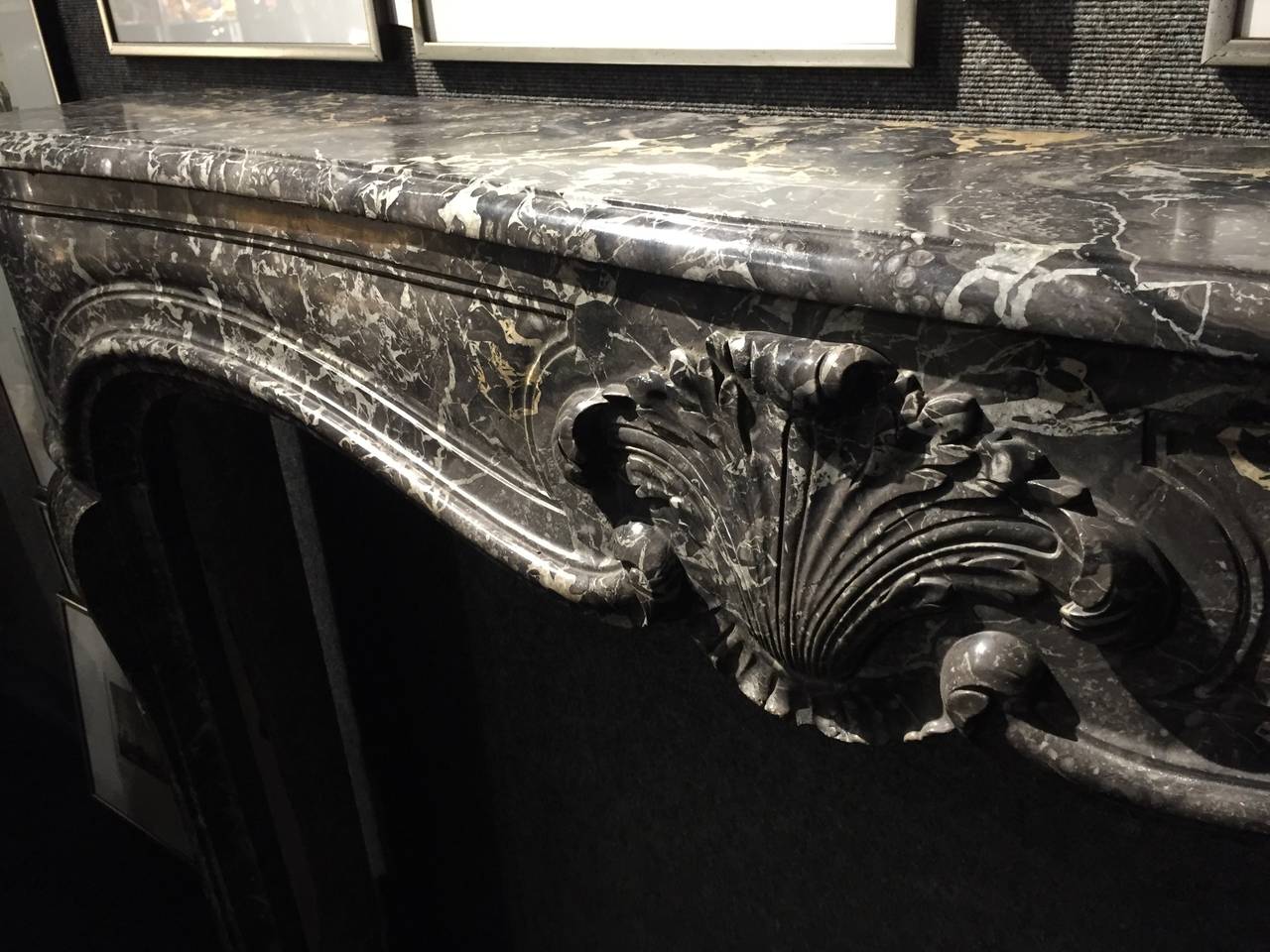 A great quality of a French antique Louis XV style fireplace in marble, hand-carved, circa 1800s from Paris, France.

Rare quality of antique marble, beautiful handcrafted flower-shell on the middle of the mantel, panels on sides and legs. Mantel