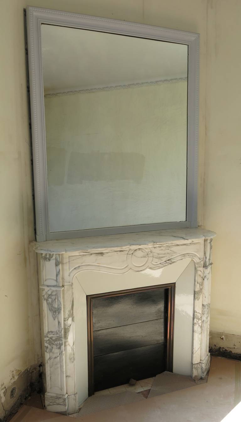 A French Parisian antique marble fireplace with wood mirror handcrafted circa 1880 in Paris, France. A classic Louis XV style.

Great quality of white marble with beautiful grey-blue (large) veins, with original firebox.

Possible to use it as