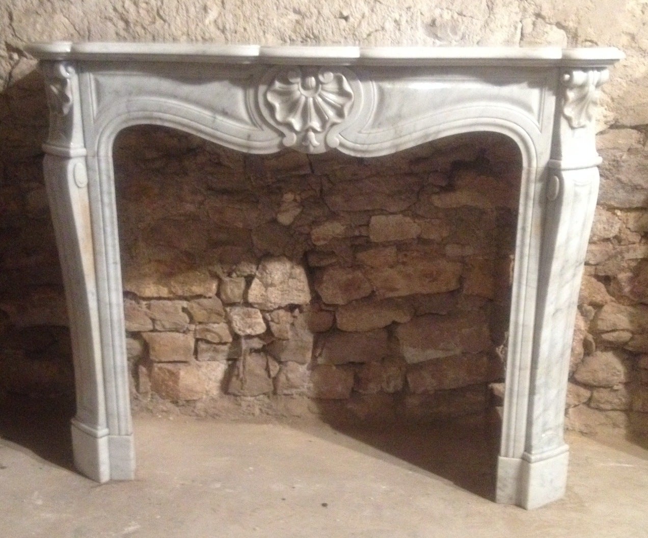 A French Parisian Louis XV style fireplace hand-carved in white marble, circa 1800s from Paris, France.

Great quality of art work from that period, with beautiful sculptures on the middle and sides of the mantel, scrolls on the sides of the