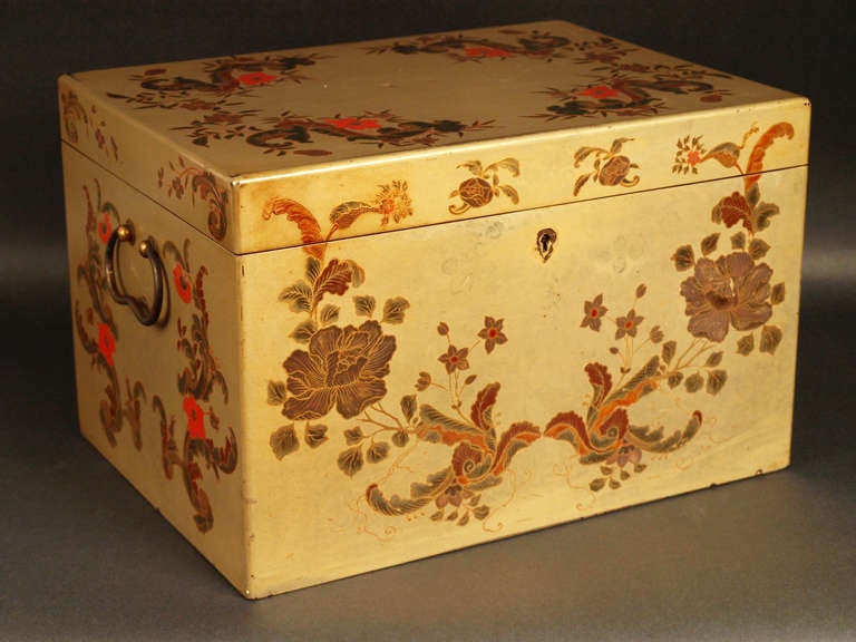 A Cantonese Chinese export lacquer tea box, decorated with gilt heightened colored volutes and flowers on a beige ground, the interior fitted with paktong box. Silver label in the inside 