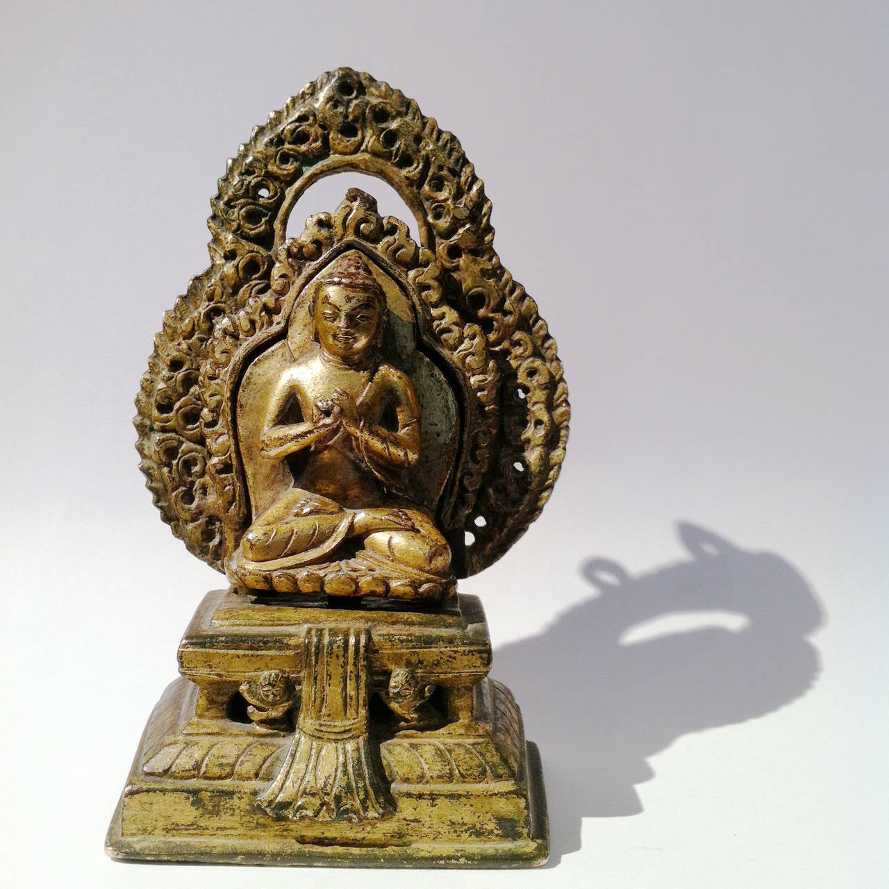 A very nice partially gilt bronze figure of Buddha sitted in dhyanasana on a rectangular stand. His hands are in Dharmachakramudra, wich is a position that is not very usual.  The buddha is sitten in front of a mandorla that is cast at the same