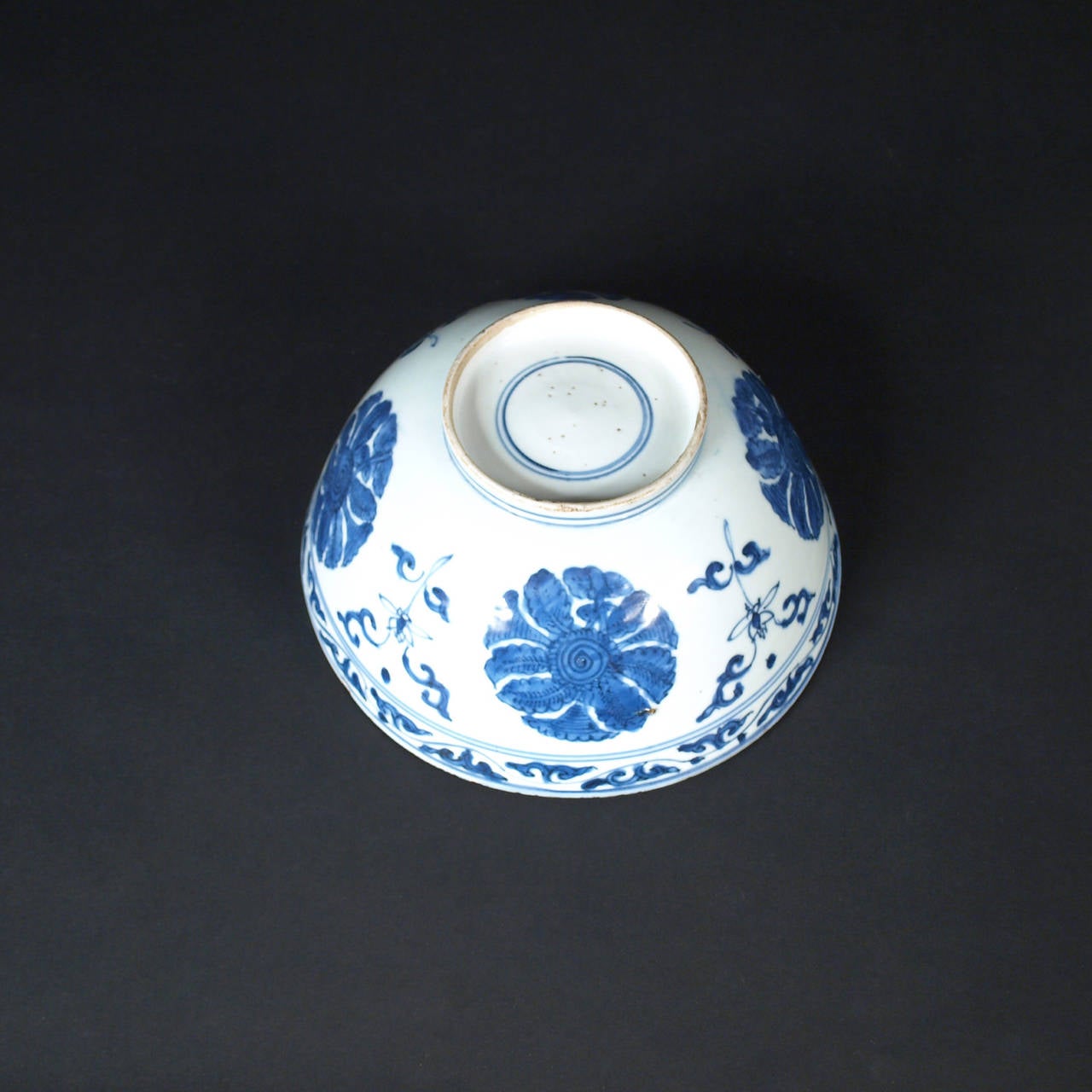 A very nice undercover blue and white Chinese porcelain bowl, outside decorated with flowers and scrolls, inside with a landscape and a lotus flower.
China, end of the 16th century, Wanli, Ming period.

For a similar piece: Rijksmuseum Amsterdam,