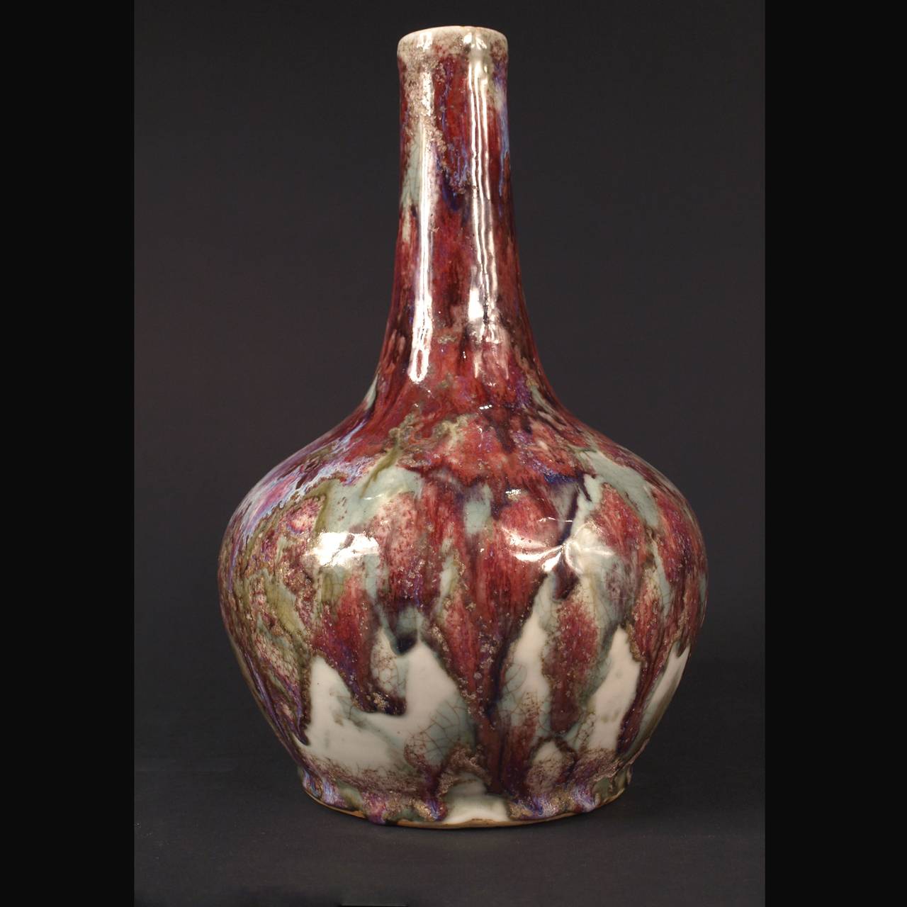 A CHINESE FLAMBE BOTTLE VASE , 19TH CENTURY 
The compressed body surmounted with a thick cylindrical neck, covered over all in a speckled glaze ranging from light lavender to crushed strawberry tones
Diameter: 22,5 cm; 34.5 cm. high 
Qing Dynasty.