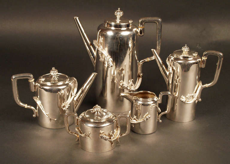 Chinese Export Silver set of 5 pieces comprising a teapot, a coffee pot, a chocolate pot a covered sugar bowl and a milk jug. The decoration is of 2 applied opposing dragons against a plain background. 
Four of the pieces bear the mark of Luan Hing