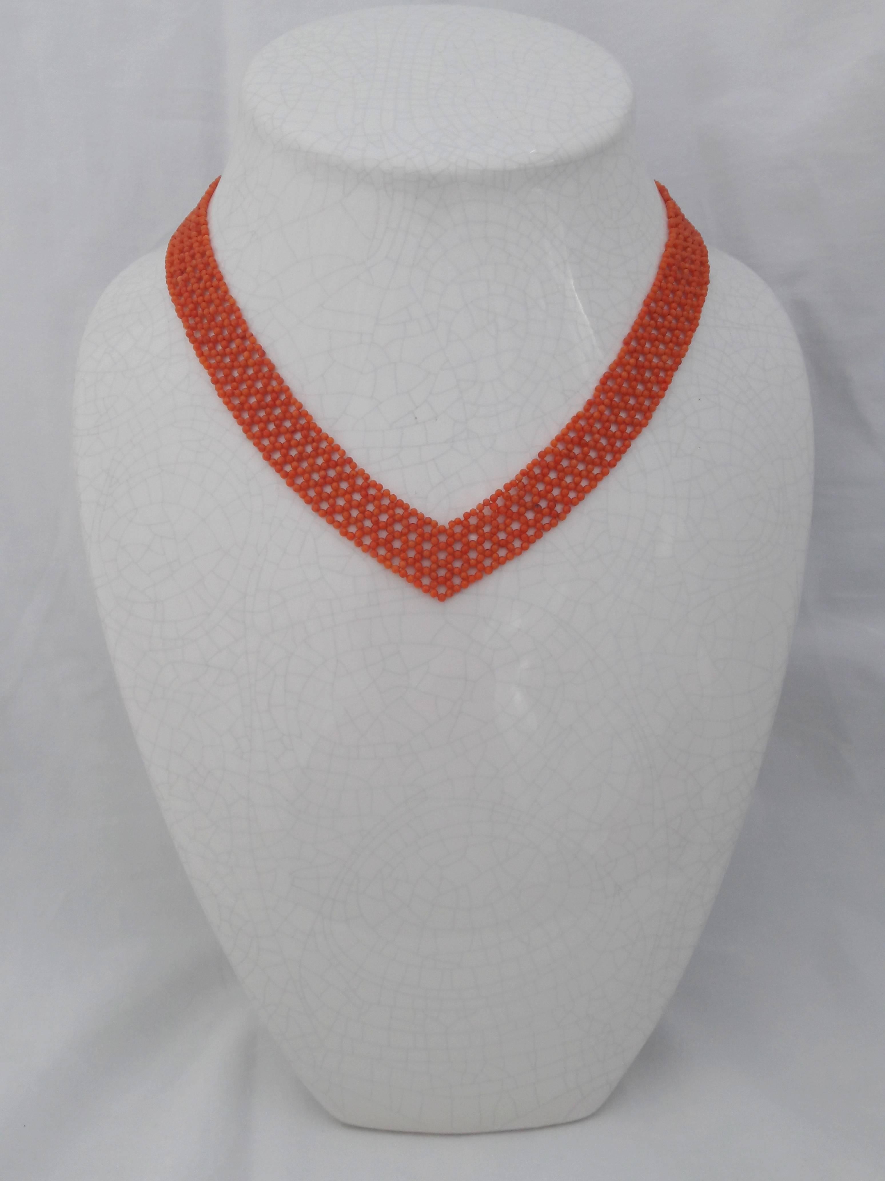 Ce magnifique collier en forme de V est conçu pour allonger n'importe quel décolleté. Des perles de corail tissées de manière complexe se rejoignent au niveau d'un fermoir en plaqué or argent. Cette pièce de jour ou de soirée est élégante en soi ou