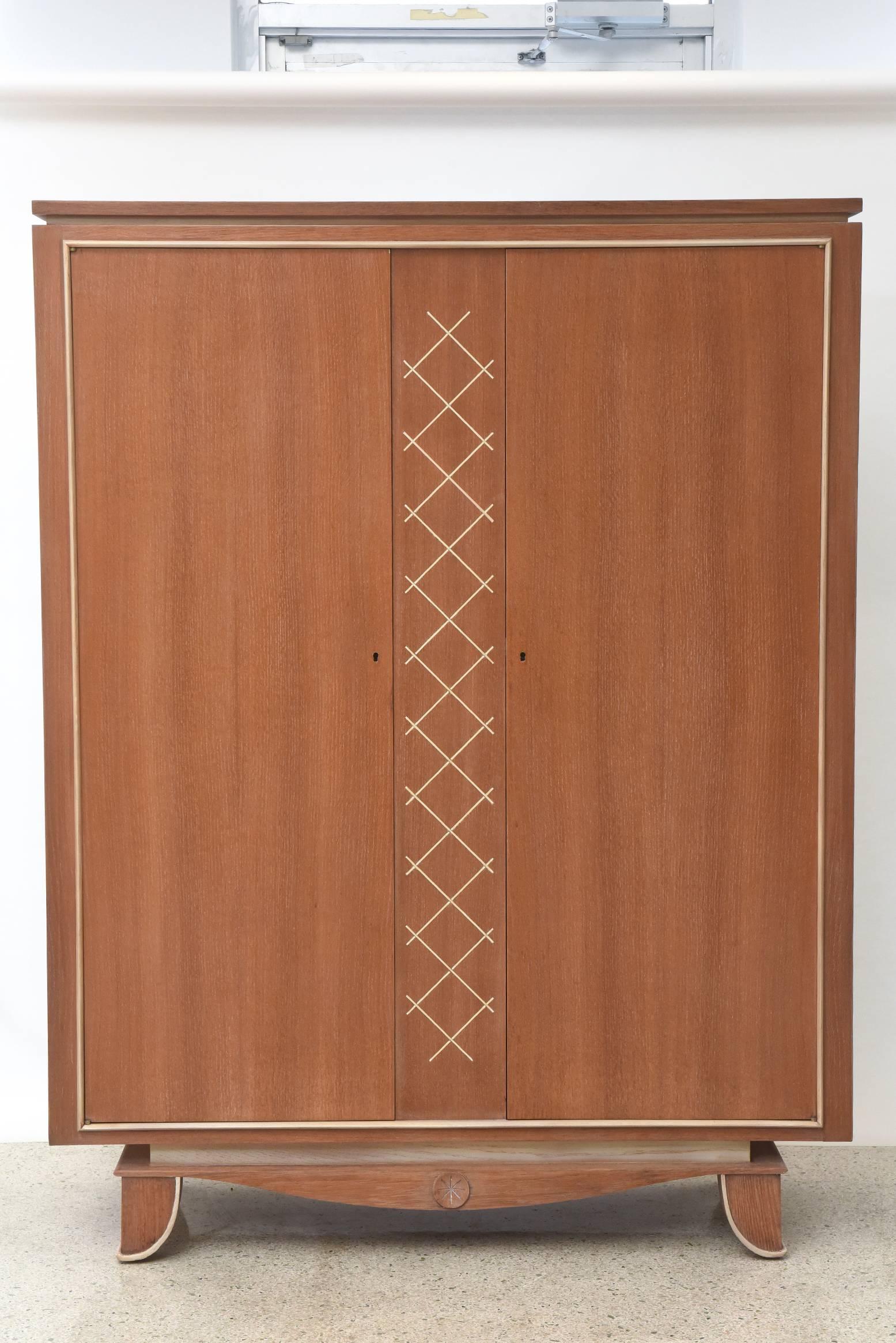 This French modern limed oak and parchment tall cabinet by designer Pierre Petit was made in the 1940s. The cabinet stands on raised carved legs with interlacing frieze in the centre. It has 2 doors with inlaid parchment in a cross hatched pattern