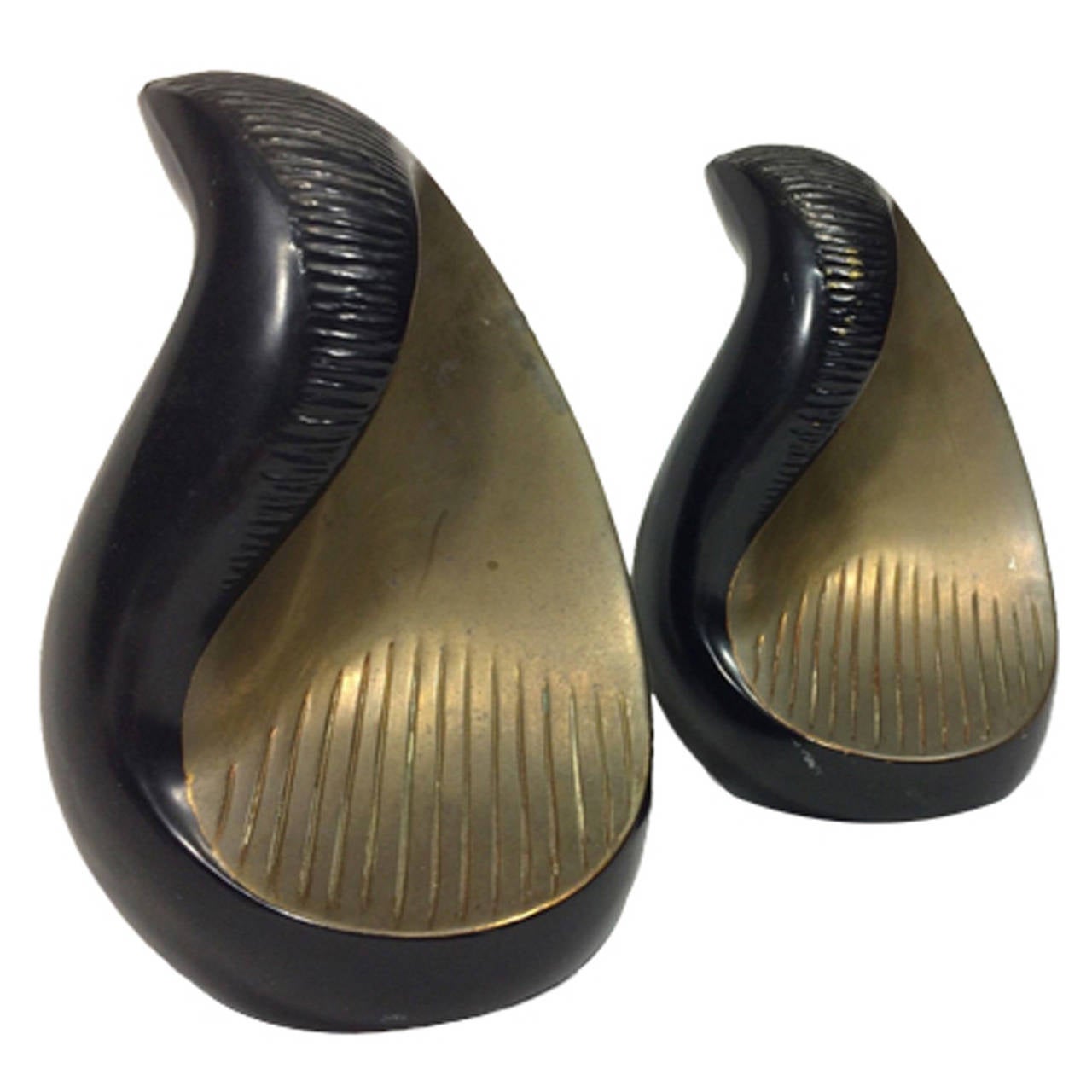 A pair of mid-century sculptural bookends. The incised bookends feature a curved shape in a two-tone brass finish and a textured exterior