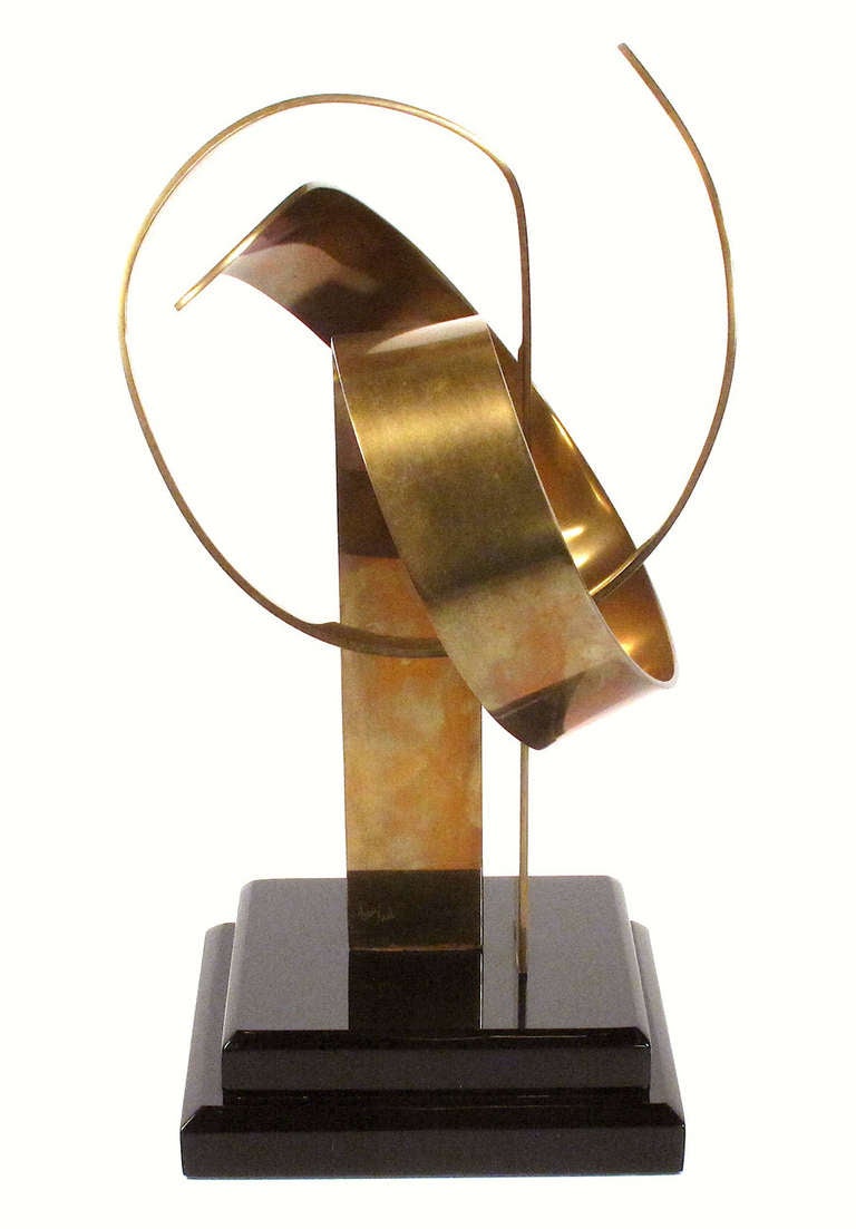 A striking brass sculpture by Van Teal on a tiered black lacquer stand. Signed.
