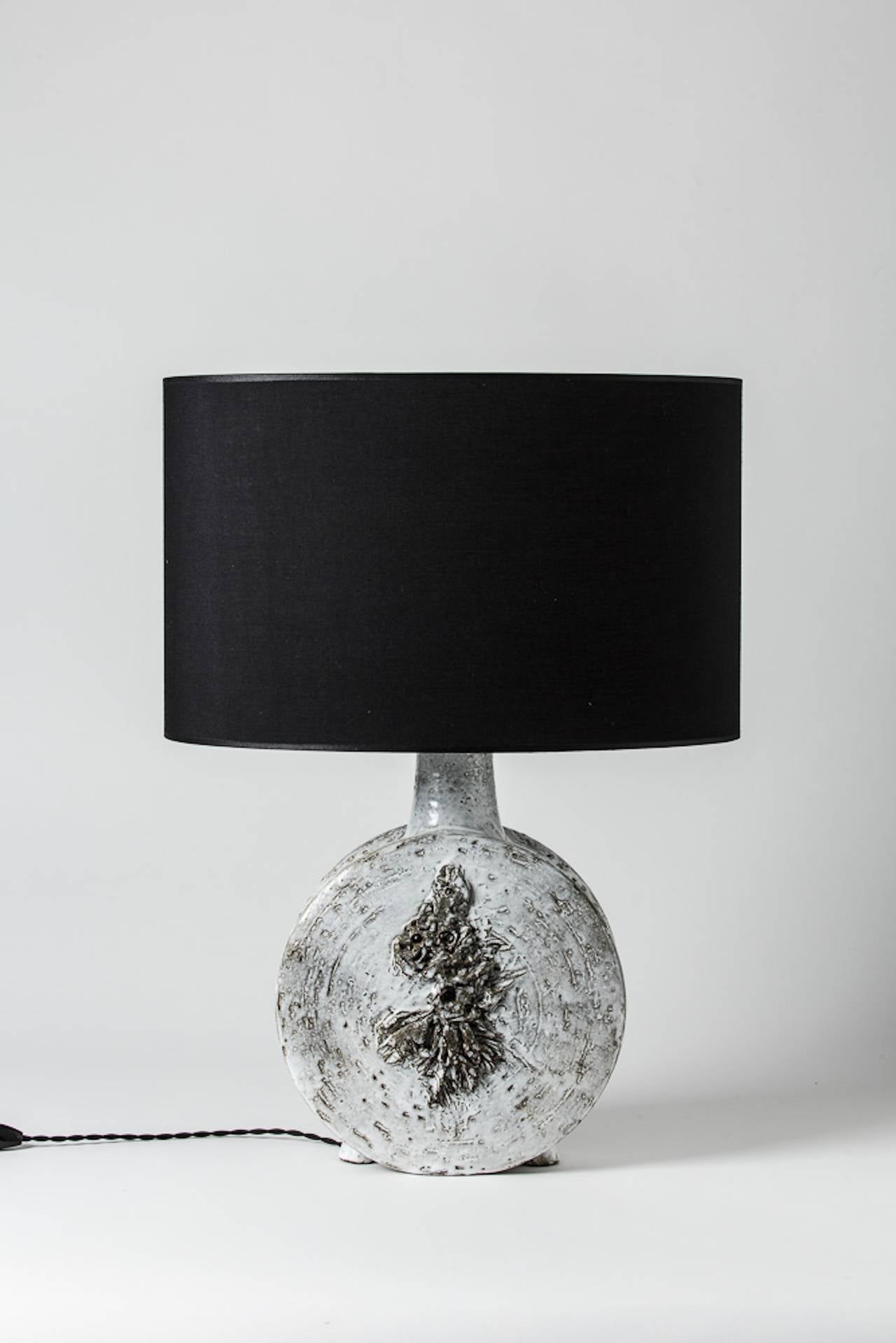 An important stoneware lamp by Huguette & Marius Besson.
White glaze decoration.
Unique piece.
Signed under the base,
circa 1970.

Height with shade: 25'. 
Height without shade: 18'.
Width: 11' 1/2.
Depth: 3'.