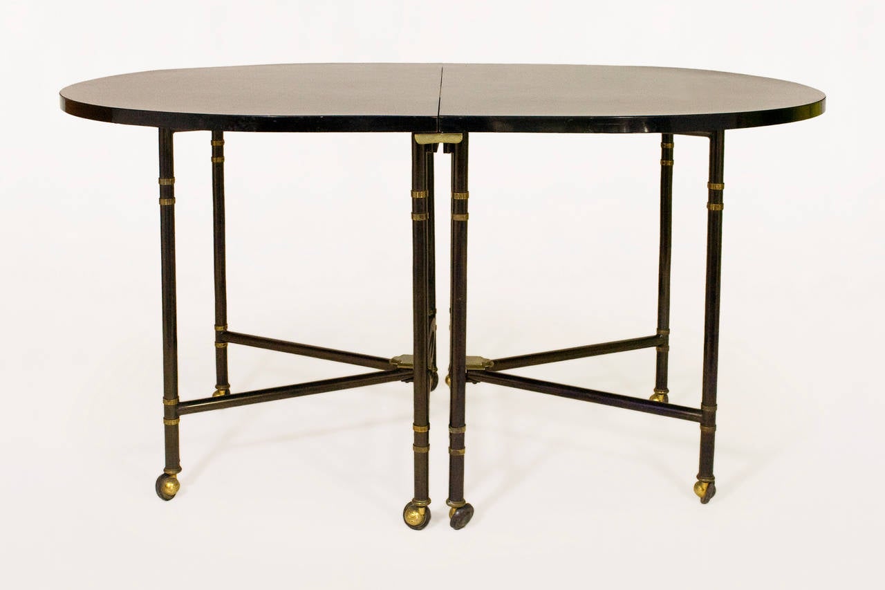 Maison Jansen Royale dining table.
Brass-mounted and ebonized and steel.
Oval shaped black painted wood top.
Legs with brass double collar and cuffs.
Stamped on brass casters, 'Shepherd Belgium G B U.S.A Swiss France 970997 patents,'
circa