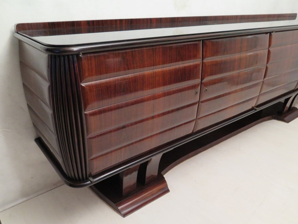 Beautiful and original, this sideboard of Dassi, with four doors. Very beautiful woodworking on the corners. On the top has a black glass.