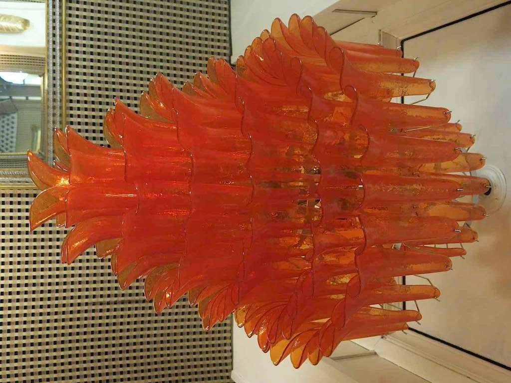 Chandelier by Mazzega from Murano. The color of this beautiful and very classic Mazzega chandelier is very strong orange. Its construction is made of curved glass tiles hanging around an iron structure. Its orange color is really guessed for a