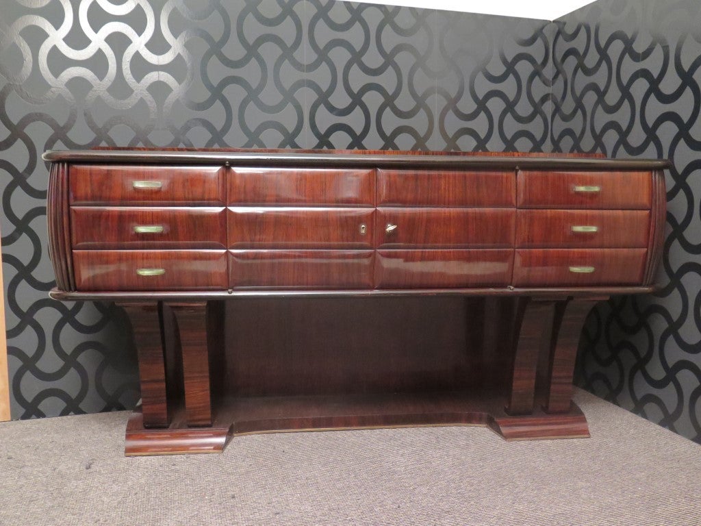 Beautiful and original, this sideboard of Dassi, with two doors and six drawers. Very beautiful woodworking on the corners. The handles are made of glass. On the top has a black glass.