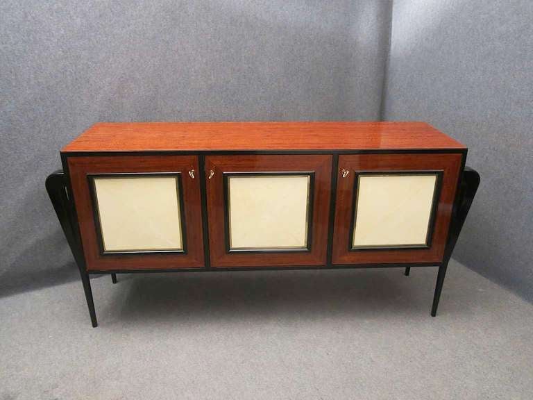 Extremely elegant French art deco sideboard with three wooden doors of lemon Tinto brass edge and central part in parchment. Very special, the side legs in black lacquered wood. Roomy and spacious the inside of the sideboard. An object very very