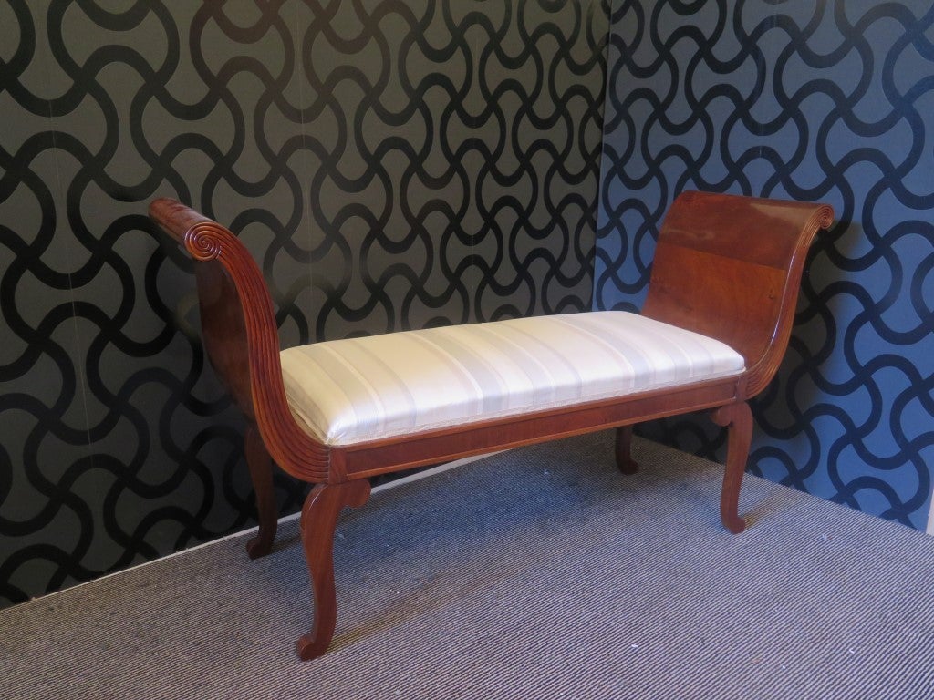 1890 bench, veneered in walnut. Simple and elegant, composed of a upper body with two large wooden arms made like a comma, and a seat covered in striped silk fabric. The bench is raised from the ground by four walnut saber legs. Note the manual