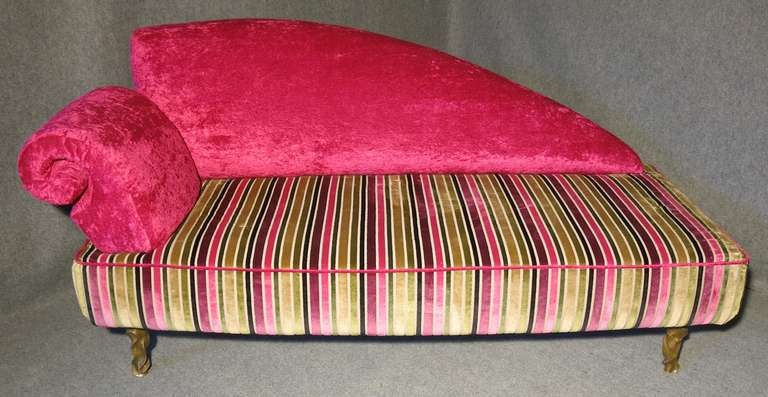 Sofa upholstered in two-tone velvet, a shocking pink combined with a striped multicolored fabric (black, pink, green, beige).
Dormeuse formed by a large rectangle of base, with rounded backrest and shell-shaped armrest.
The four legs are the