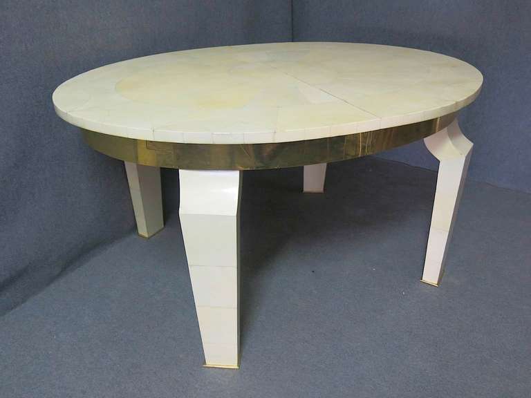 Extendable table, oval shape. Very nice design on its top, its chic brass band. Particular also its legs with the end of the brass slippers are.
