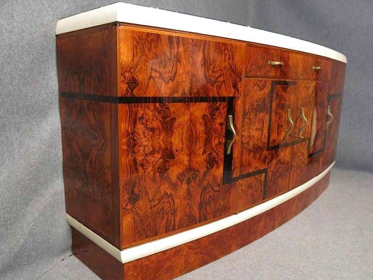 Art Deco buffet with black marble top, walnut body and inserts in Makassar ebony. two beautiful strips of parchment in a top and a bottom finish very well the sideboards. 
the handles are made ​​of brass.
It has four doors and a drawer at the top.