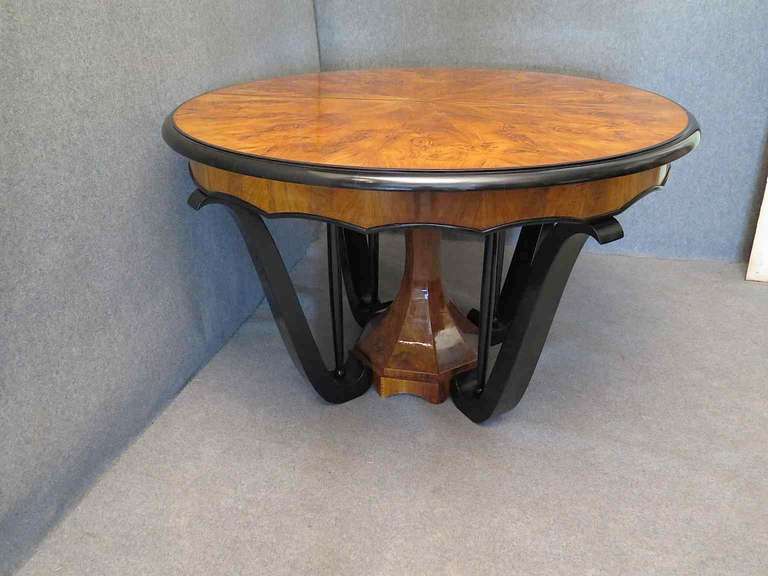 An important Biedermeier table, with a very big top, and a very particular leg.

The table top is veneered with a beautiful walnut with parts forming a picture. The central leg is formed by a central massive of walnut and by four legs black