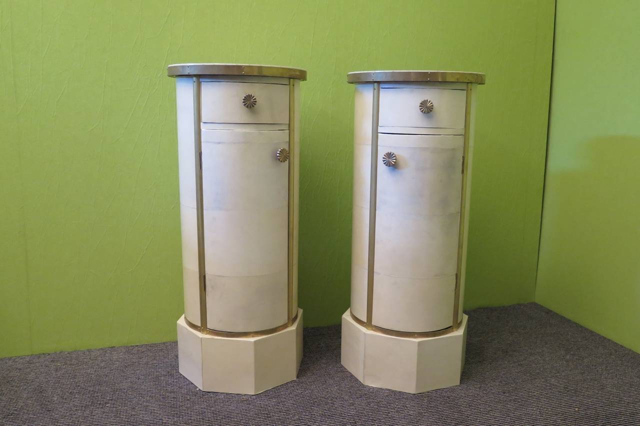 Two wonderful tables in the column, all covered in parchment and decorated of brass. Two small drawers and two doors. Very pretty as bedside tables for a bedroom or as columns.