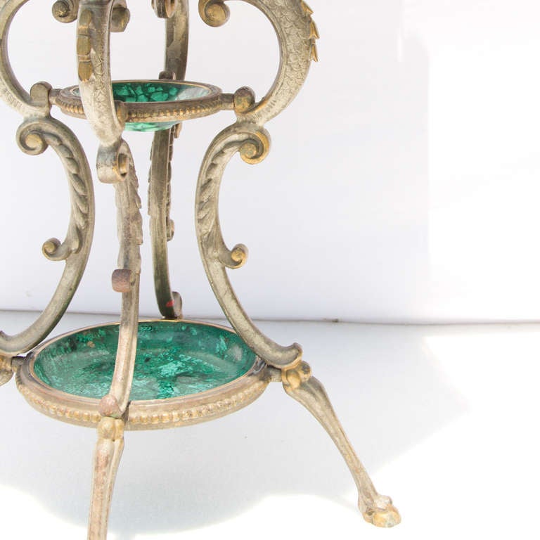 A mirrored top with malachite sections on this partially gilded cast iron center piece table.