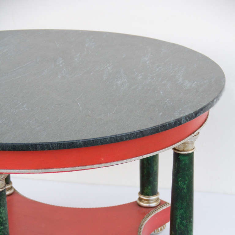 A green marble top round side table. With coral red, silver and faux malachite columns.
