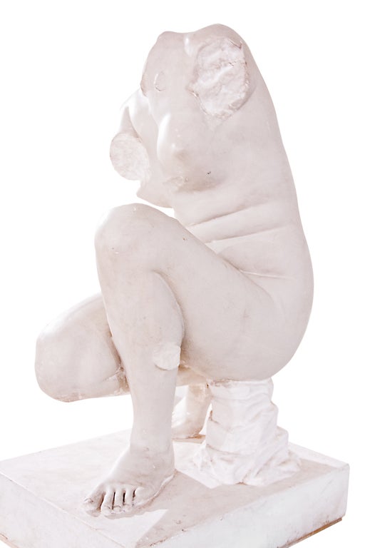 A plaster life size statue of a kneeling Venus.