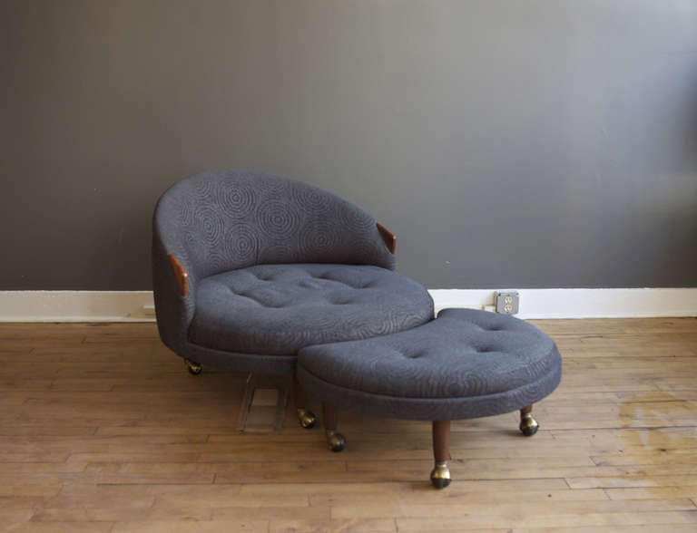 A comfortable circular lounge chair by Adrian Pearsall with crescent-shaped ottoman. Legs are tapered walnut with brass casters. Vintage geometric fabric is not original to the piece, but in excellent condition.