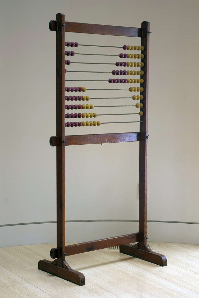A large vintage abacus supported by a vertical frame with red and yellow counting beads, ca. 1920. Retains old finish exhibiting a wonderful patina. 

A charming, decorative piece.