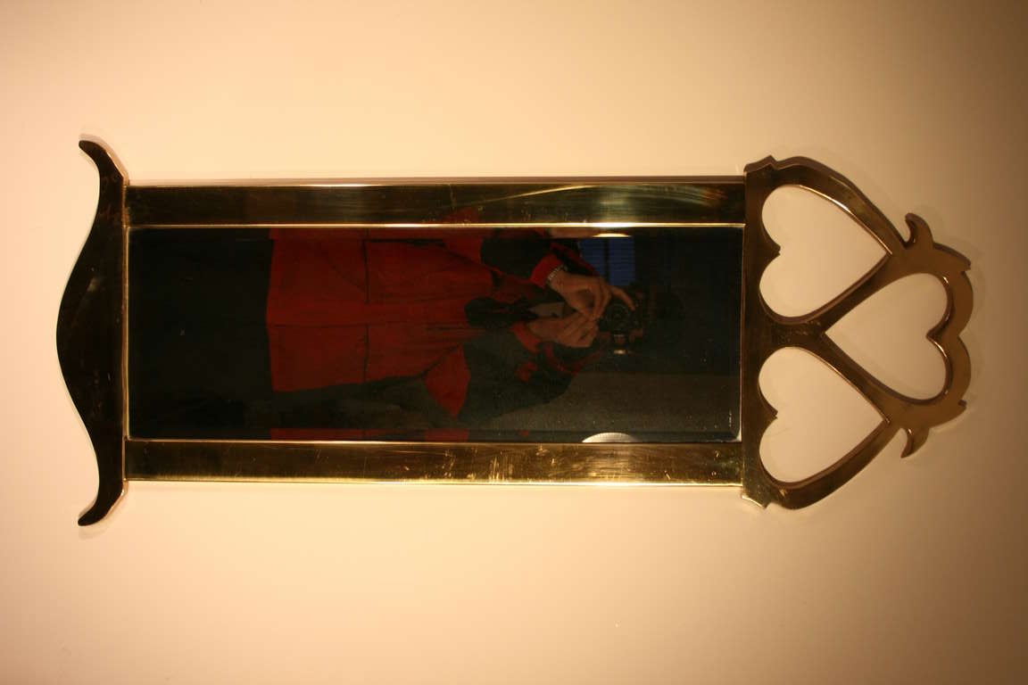 A beautifiul, solid cast brass framed mirror with a trio of hearts on the top and an inverterd yoke bottom. The mirror is beveled and measures 10