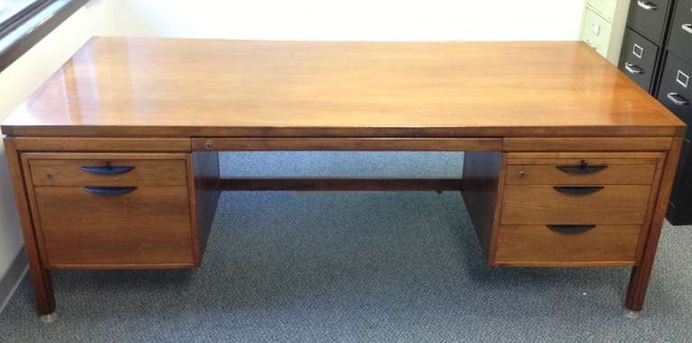 A classic Risom design. A large, executive desk with ample proportions. Walnut case with two banks of drawers and two pull-out writing surfaces. The left bank of drawers includes a file drawer.