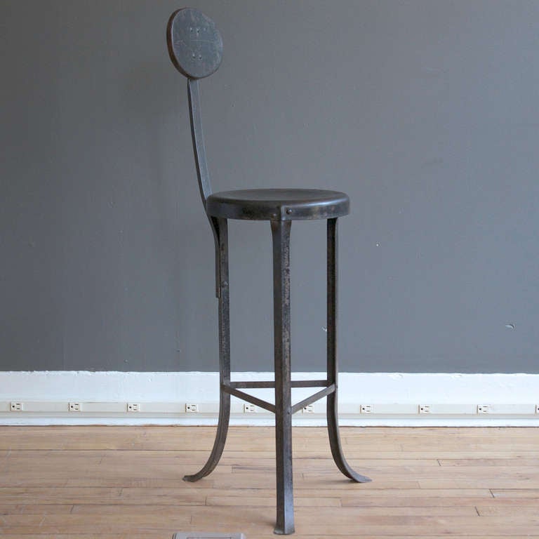 An industrial metal shop stool with three curved legs, ca. 1913.