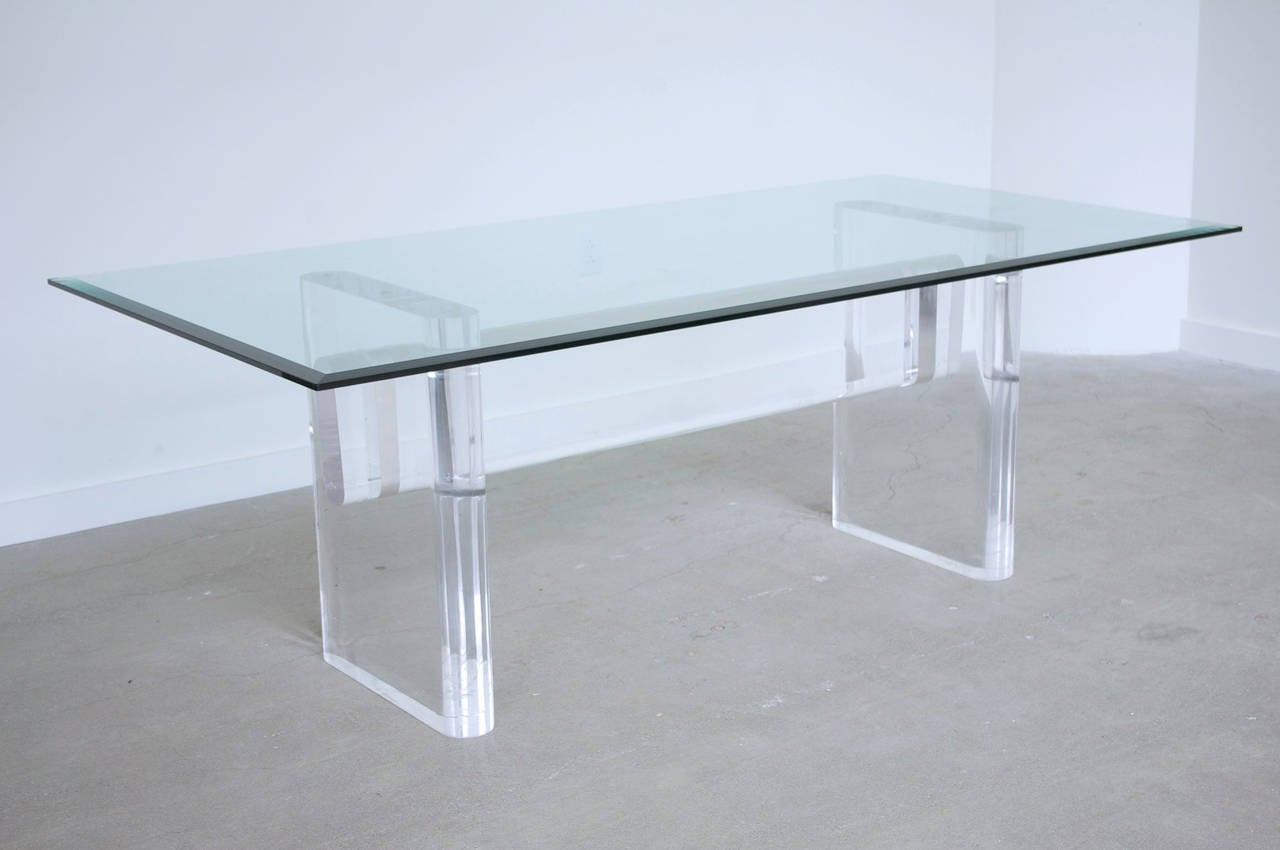 An impressive Lucite dining table with glass top by Karl Springer, circa 1980s. The sculptural base consisting of two thick legs joined by cross stretcher. Facsimile Karl Springer signature to bottom of one leg. 

Base measures: 62