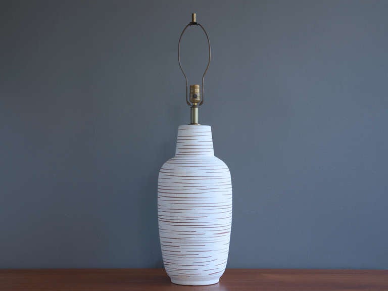 A large ceramic table lamp by Design Technics, circa 1950. Featuring a matte white textured glaze with terracotta stripes. Retails original mounting brass hardware and socket. 