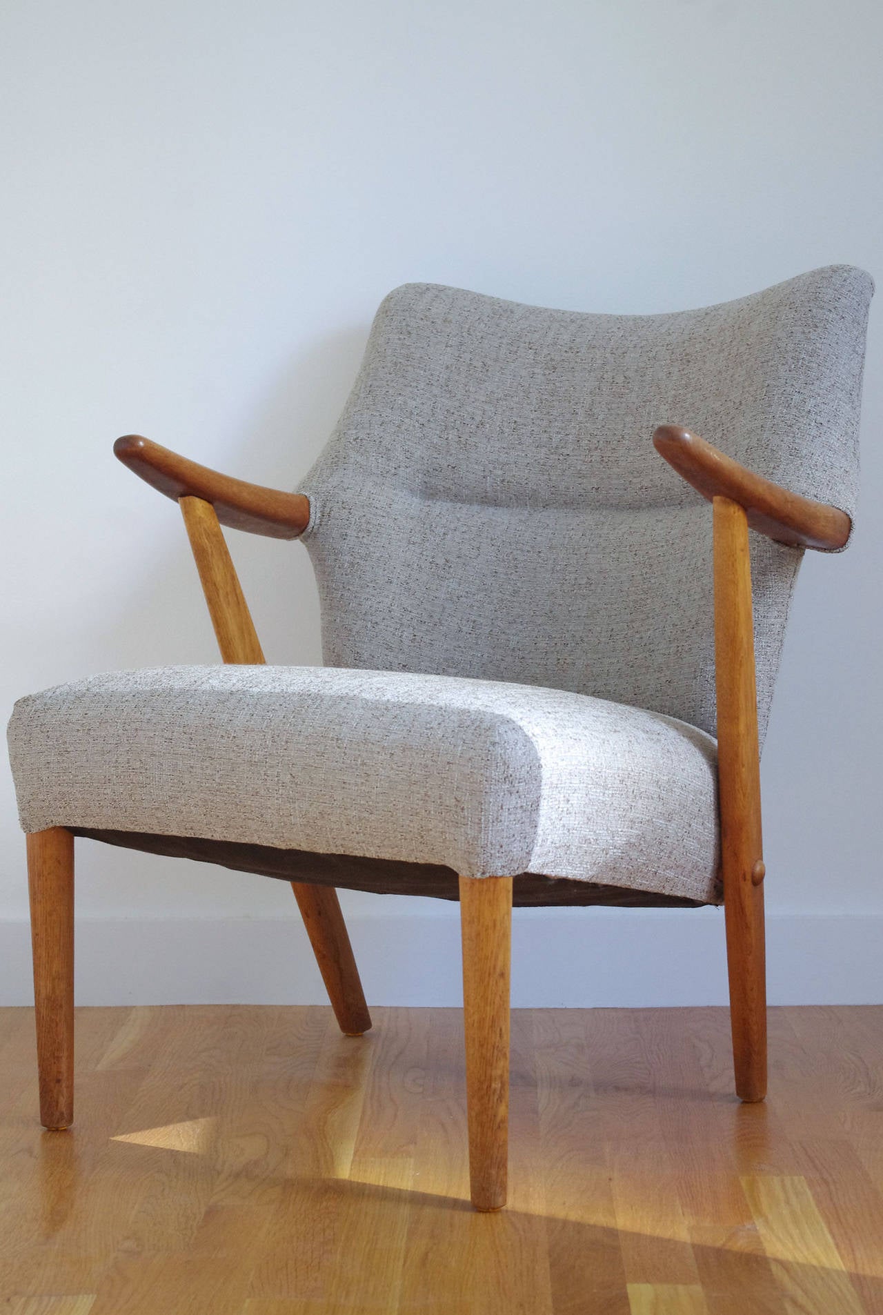 A pair of upholstered lounge chairs in the style of Aksel Bender Madsen possibly for Bovenkamp, circa 1950.

Featuring teak arms and oak legs. Recently upholstered in a gray tweed fabric.