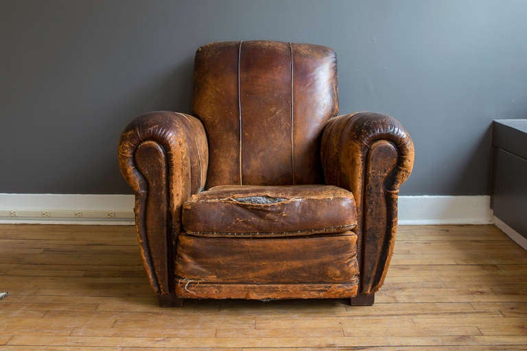 Purchased at the Paris flea market, this Art Deco distressed brown leather lounge chair is in AS FOUND condition.  The distressed leather is beautiful and inviting with a rich patina and character.